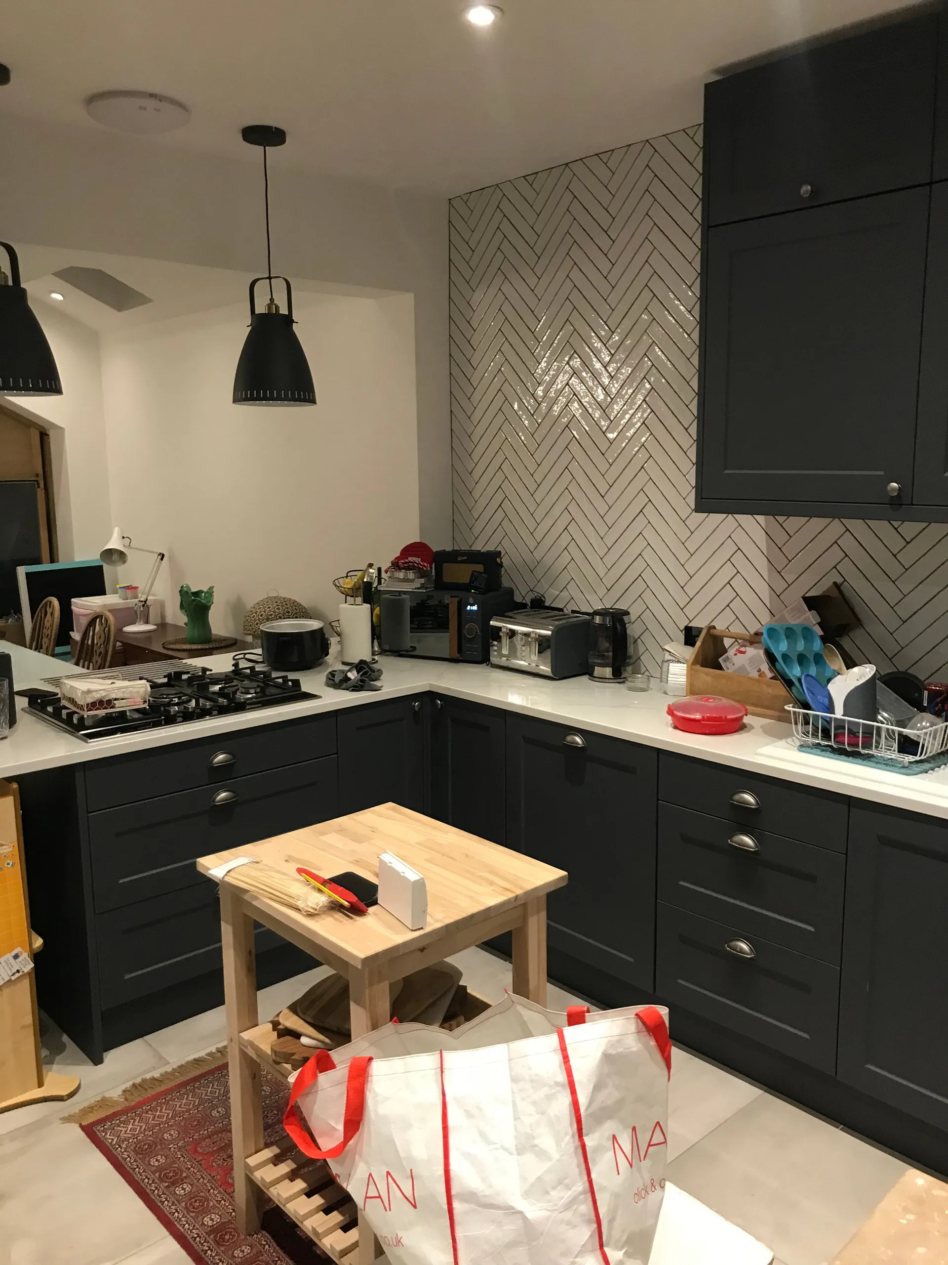 Finished kitchen with dark cabinets and herringbone tile backsplash