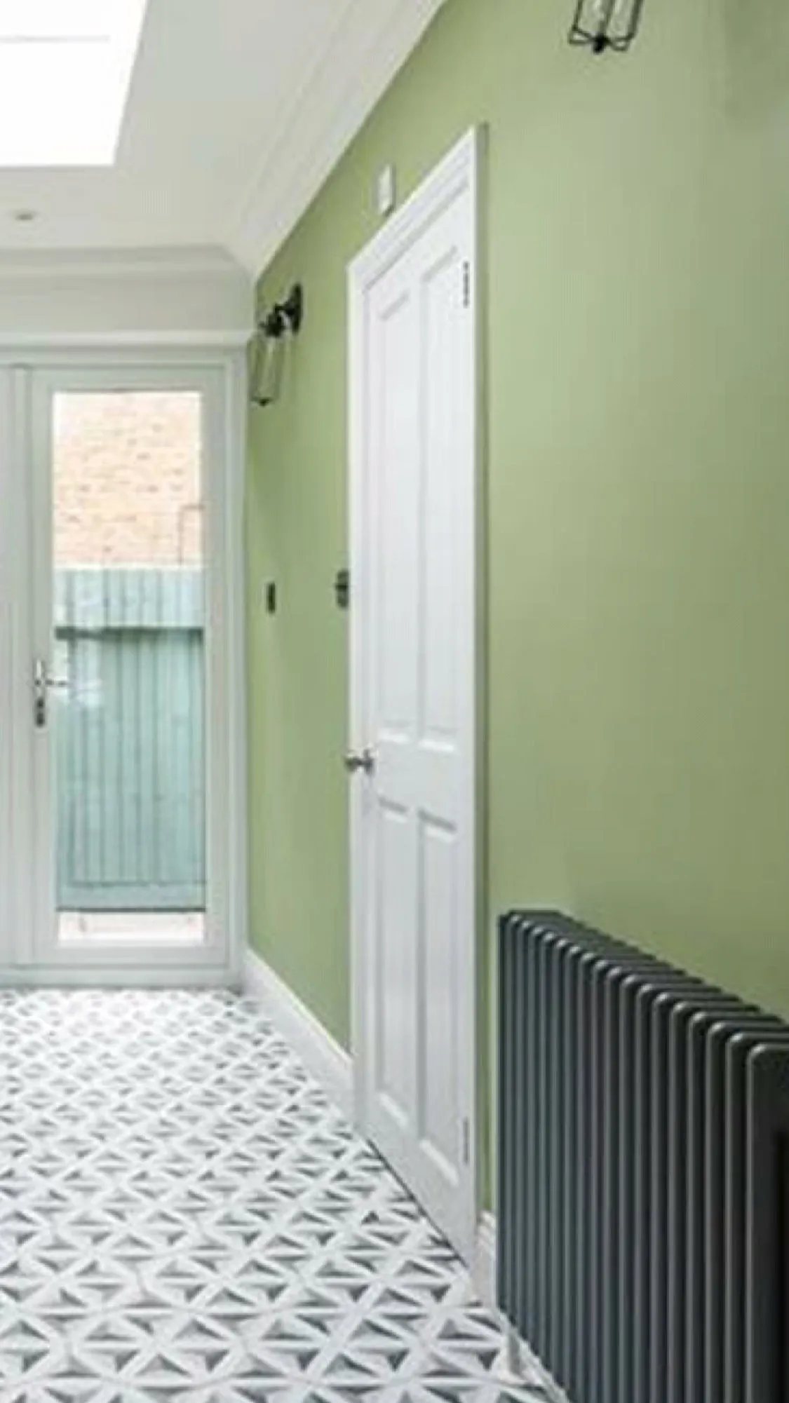 Hallway with sage green walls, skylight and cast iron radiator