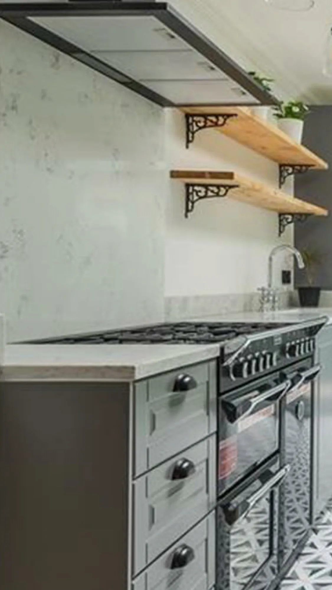 Kitchen detail with range cooker, marble backsplash and wooden shelves