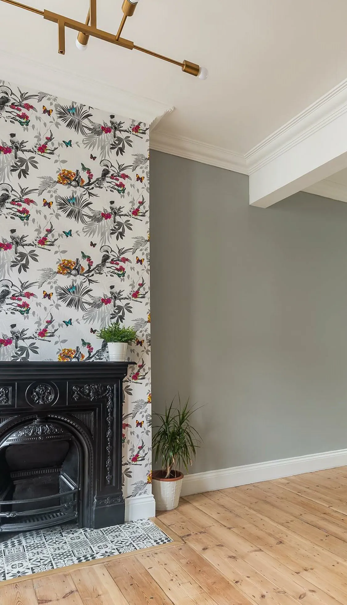 Living room with Victorian fireplace, floral wallpaper and brass chandelier